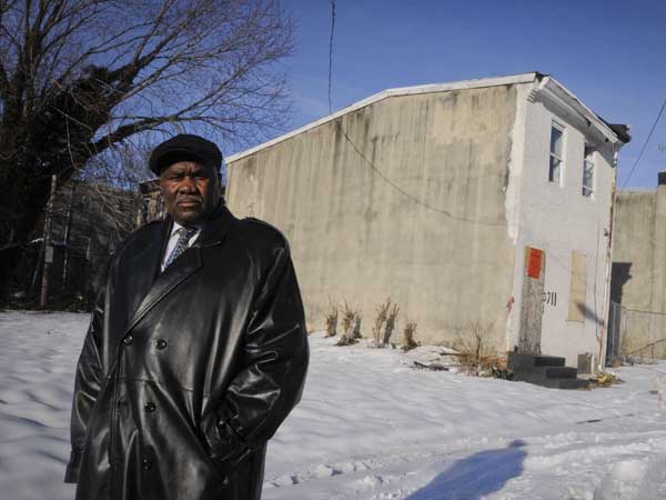 Rev. Harry Moore, pastor of Mount Olive Baptist Church, stands beside a house at 3711 Melon St., in Mantua where he will preside over a "funeral" for the house in an attempt to recognize Mantua´s past, embrace its present and celebrate its potential rebirth with the help of a federal Promise Zone. ( RON TARVER / Staff Photographer ) February 17, 2014
