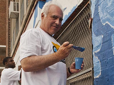 Eagles owner Jeffrey Lurie helps paint a mural at Comegys Elementary School on Wednesday. (Elise Wrabetz/Staff Photographer) 
