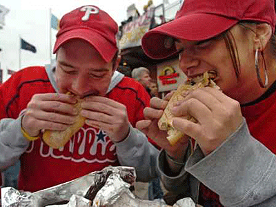 Two Phillies fans enjoy a meal from Rick&acute;s cheesesteak in Ashburn Alley, in this file photo.  (Clem Murray / Inquirer)