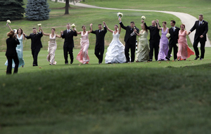 The wedding party romps for the photographer on the golf course of the Springfield Country Club before the reception for 165 guests. The bride gave her bridesmaids 12 color options for their dresses, and got a rainbow party in light pink, aqua, champagne, cantaloupe, mint green and iris purple. They chose all-white bouquets of a single flower type; the bride's bouquet combined all.