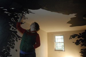 An empty suburban house has become a temporary gallery for the multimedia works of a group of students from Temple's Tyler School of Art. Megan Bartley-Matthews paints shadows in a room.