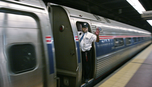 A conductor wavesas an Amtrak train leaves 30th Street Station for New York.Travelers point to cost and time savings.