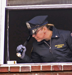 An investigator examines the window from which a woman jumped yesterday.