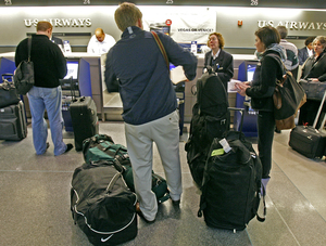 US Airways customers check bags at Philadelphia International Airport. Due to exceptions, the airline expects the fee to affect 8 percent of passengers.