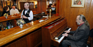 Father John D'Amico plays for bar patrons and bartender Joe Henry at the William Penn Inn in Ambler. D'Amico, a former Catholic priest, will perform at a free concert tomorrow night at Immaculata University.
