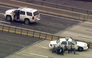 Police take cover behind cruiser in standoff with man in white SUV yesterday on the Walt Whitman Bridge. The incident caused the bridge to be closed in both directions during the evening rush hour.