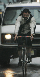 Appearing almost as if he is about to be run over, an unidentified bike messenger on his appointed rounds pedals his way along a rain-covered Market Street near City Hall yesterday.