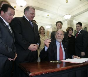 Gov. Corzine signs the paid-family-leave bill into law as two of its primary backers, Assemblyman Nelson Albano (left) and Sen. Stephen Sweeney (second from left), watch.