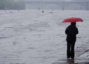 On a miserable day to watch and to participate in a regatta, a spectator yesterday looks toward the Strawberry Mansion Bridge as competitors in the Dad Vail Regatta race on the Schuylkill.