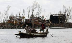 Villagers steer a boat past the town of Pyapon in Myamnar's Irrawaddy delta. The boat that sank yesterday was carrying rice, drinking water and other goods for more than 1,000 survivors of the May 3 cyclone. The four aid workers aboard were safe.