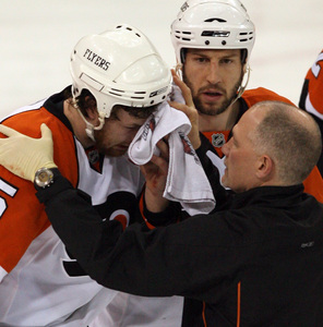 R.J. Umberger shows concern as Flyers trainer Jim McCrossin helps injured Braydon Coburn.