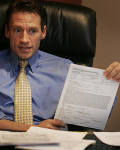 D. Scott Perrine, defense attorney for one of the men beaten by officers, displays a police "incident report" in his office yesterday.