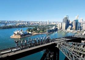Staff members of BridgeClimb wave atop the 440-foot Sydney Harbour Bridge in Australia, built in 1932.