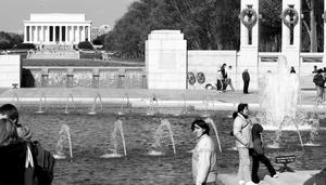 With the Lincoln Memorial in the background , tourists visit the World War II Memorial on the National Mall. To the left and right of the reflecting pool are levees built to prevent flooding.