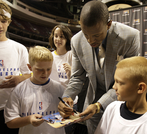 Andre Iguodala autographs a photograph for Luke Childs, 10, of Roxborough. At right is Timothy Mitchell, 10, of Roxborough.