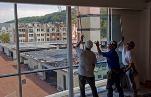 Glaziers (from left) Michael Falasca, Matt Baxter and Tom Nailly of Kennedy & Sons in Aston install a replacement window at the Millennium Three building in Conshohocken.