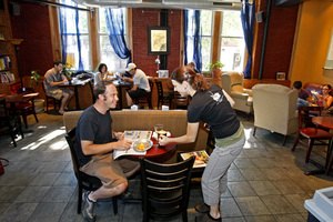 Co-owner Angela Vendetti serves Michael Neights a refill at Mugshots CoffeeHouse & Cafe in Fairmount. All the shop's coffee is fair trade, and it uses 100 percent wind energy, composts waste, and uses biodegradable material in its to-go containers.