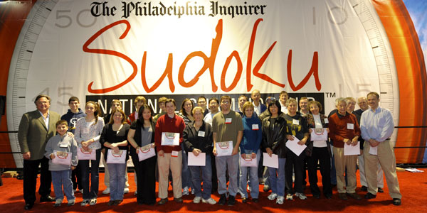 Brian Tierney, left, Publisher of the Inquirer, and puzzlemaster Will Shortz, far right, celebrate with those Sudoku National Championship contestants who finished fastest in rounds organized by age. (See list lower on this page.)<br />