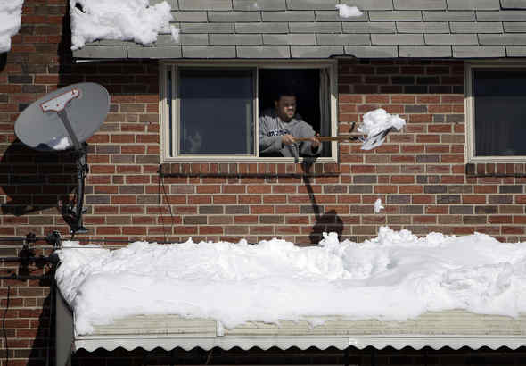 ERIC SCOTT clears snow yesterday from the awning of his home near 13th and Oxford streets in the city&acute;s Yorktown section. Scott said he was trying to prevent the cover from collapsing - a weighty possibility considering the storm dropped a near-record 28.5 inches. Story, Page 6.