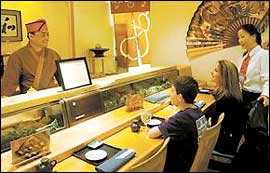 Sushikazu owner Bruce Kim builds a rapport with customers who come to his sushi bar. At right is waitress Jin Min. (Photo: Michael S. Wirtz)