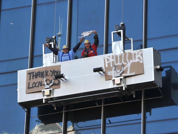Two construction workers, suspended high off the side of the new Residences at Ritz Carlton condo building, cheer for the Phillies as the parade winds its way around City Hall.   (Photo by Clem Murray / Philadelphia Inquirer and Daily News Staff Photographer)  EDITORS NOTE:  081031-Parade01cm-t  10/31/2008   Phillies World Series parade through the streets of Philadelphia.   20 of many   