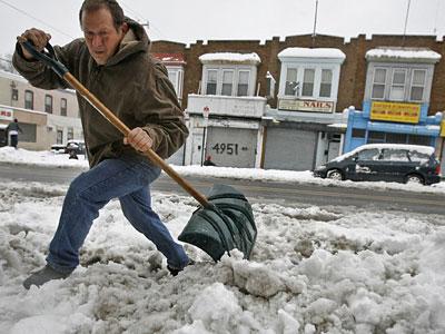Luis Gomez jumps a pile of snow along N. 5th St. He was clearing a channel to drain the water from the melting snow of Wednesday morning. (Alejandro A. Alvarez / Staff Photographer)