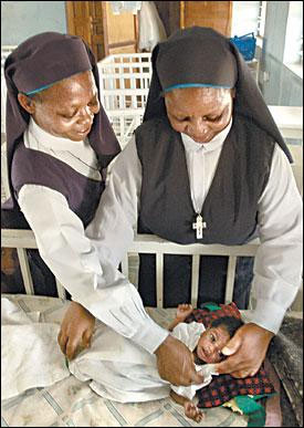 Sisters Joan Viannuey (left) and Mary Chimtuwa tend to a new arrival at the Holy Family Sisters orphanage in Gwagwalada, Nigeria.