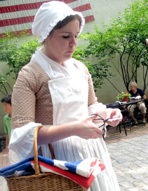 Actress Meredith Rich, as Betsy Ross, shows how to make the five-point star used in the first American flag with just one cut of the scissors.