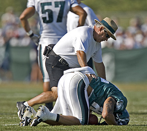 Tight end L.J. Smith, aided by defensive line coach Pete Jenkins, stays down on the practice field after reaggravating a sports hernia injury at training camp yesterday.