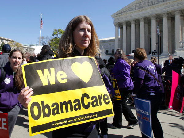 File photo: Holding a sign saying "We Love ObamaCare," a supporter of health care reform rallied in front of the Supreme Court in Washington, Tuesday, March 27, 2012. (AP Photo/Charles Dharapak)