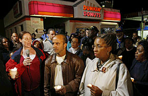At a vigil for slain Officer Chuck Cassidy last night at the Dunkin' Donuts at Broad and 66th, Heather Derussy (left) of the Guardian Angels spoke.