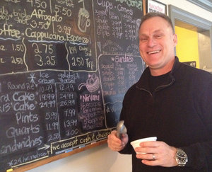 FTSMALL06 - Caption: Reece smiles in front of Scooped&acute;s homemade menu in his Exton shop. Credit: Emily Rolen